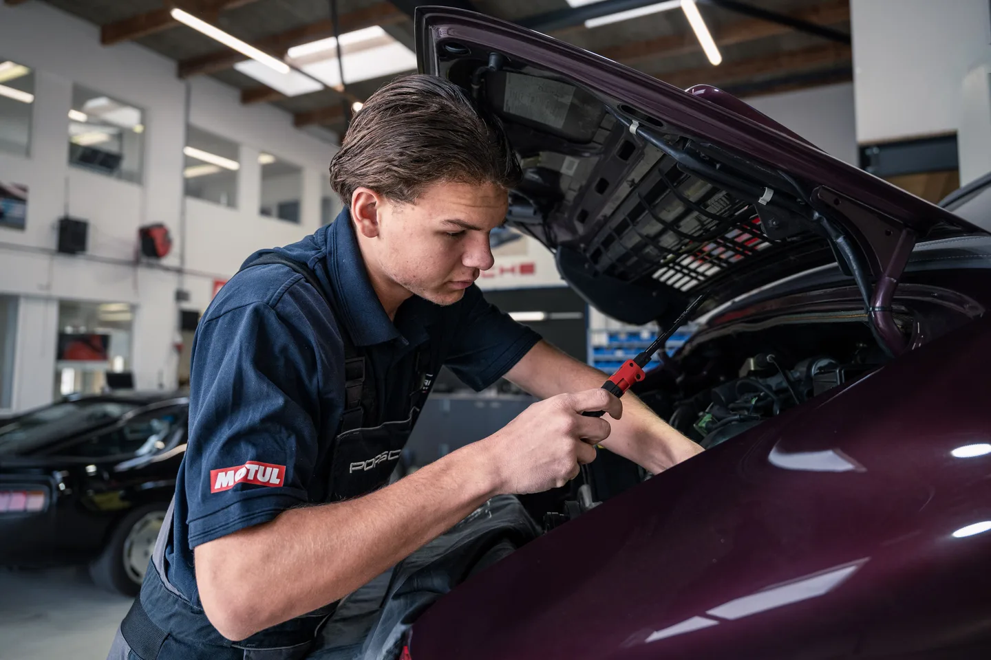 Monteur van GTAX Repair aan het werk onder een geopende motorkap