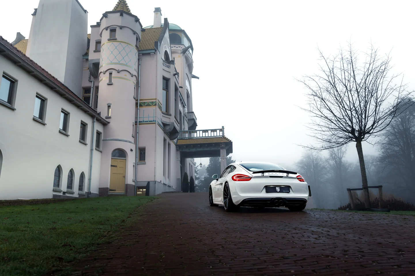 Witte Porsche bij een historisch landhuis in de mist