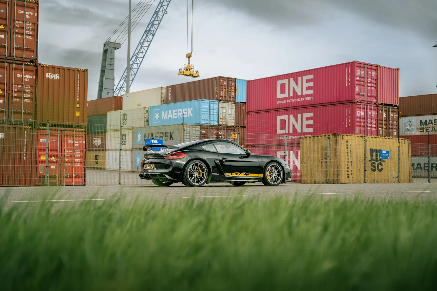 Sportwagen tussen containers op een industrieel terrein