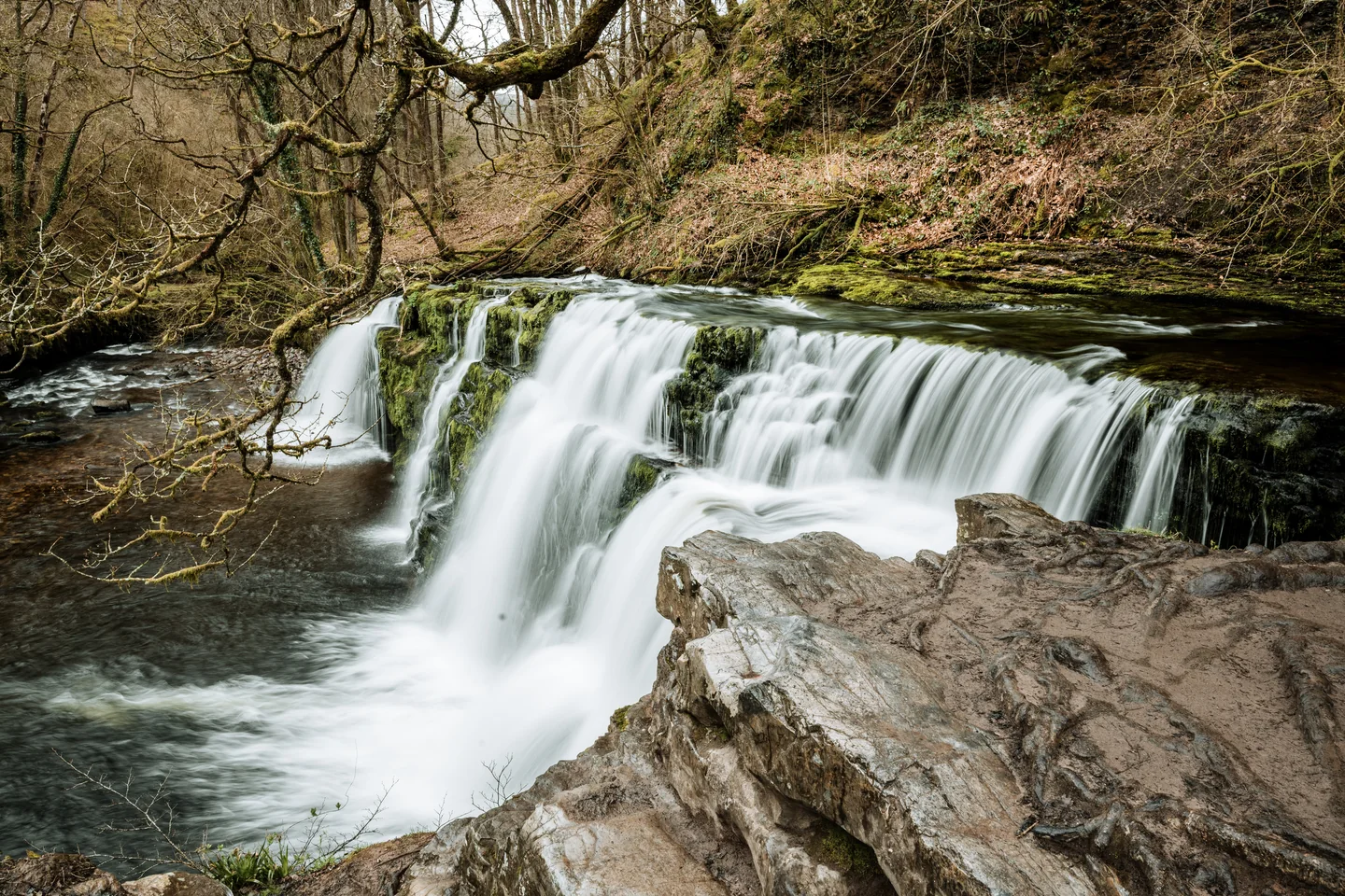 Brede waterval tussen rotsen en bomen