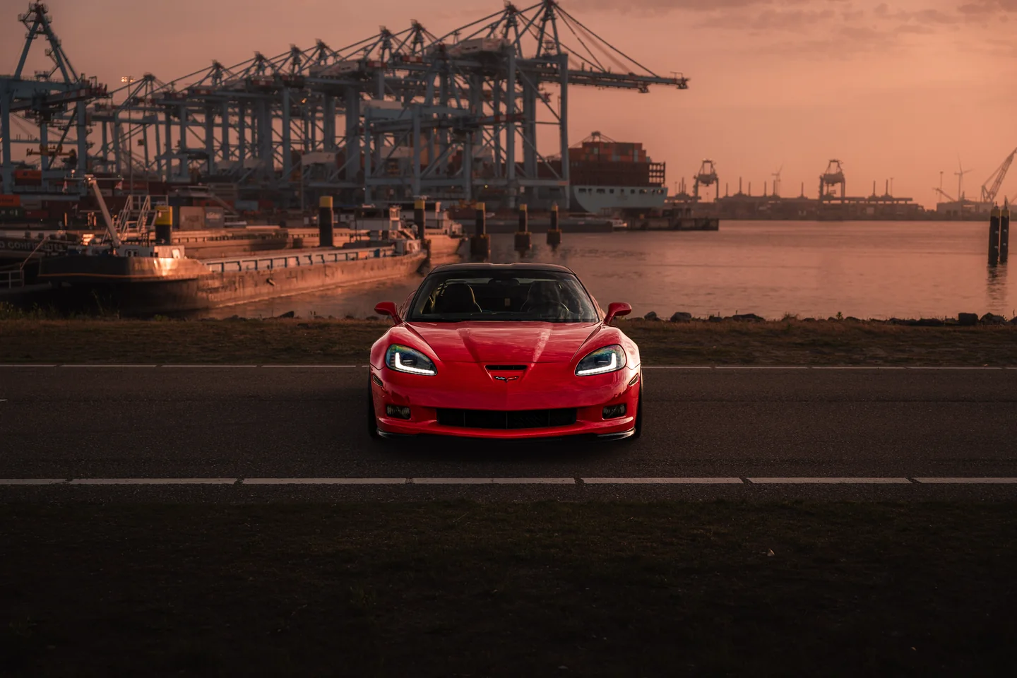 Rode Corvette aan het water bij zonsondergang