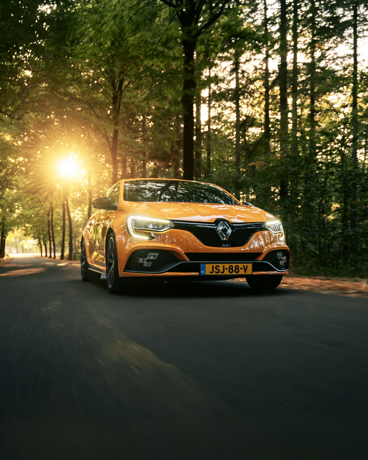 Oranje Renault gefotografeerd in beweging tussen bomen